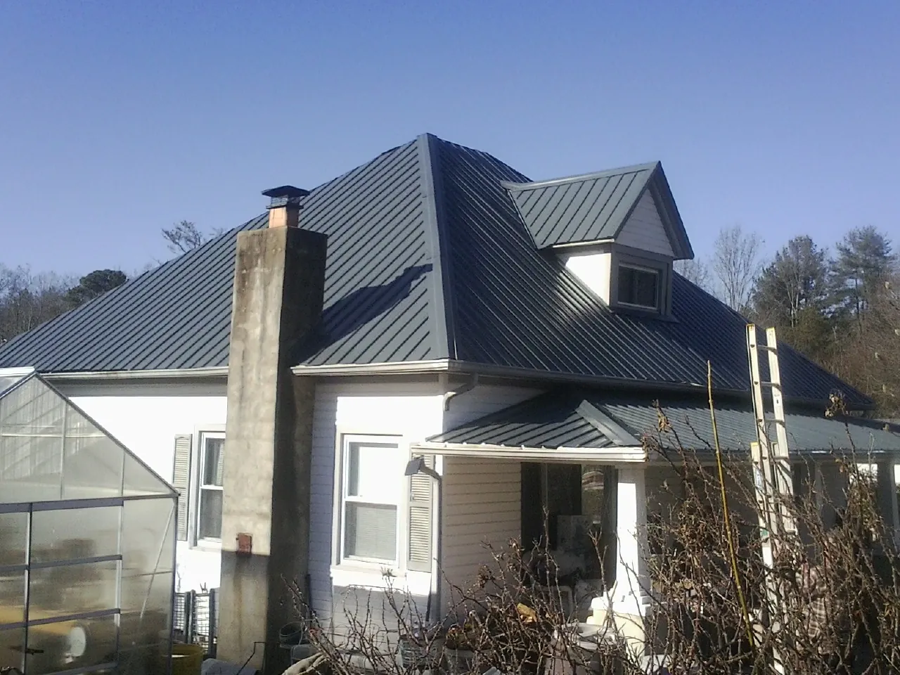 Dark blue standing seam metal roof on a white farmhouse with dormer — Slate & Tile Roof Repair by Roofing Brothers in Livermore Falls