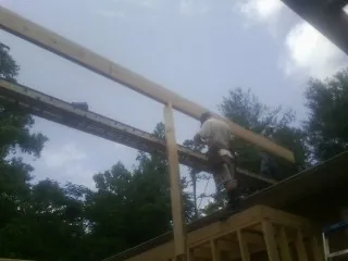 Carpenter setting a ridge beam over a new addition frame — Ice Dam Removal by Roofing Brothers in Livermore Falls