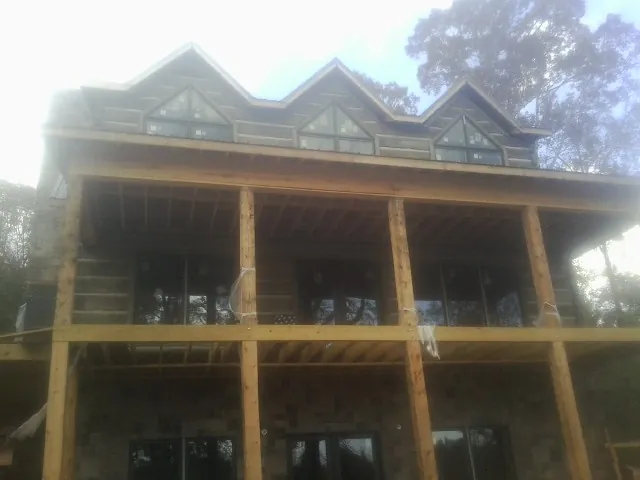 Dormers and porch framing on a large log home under construction — Roof Coating work by our crew in Livermore Falls