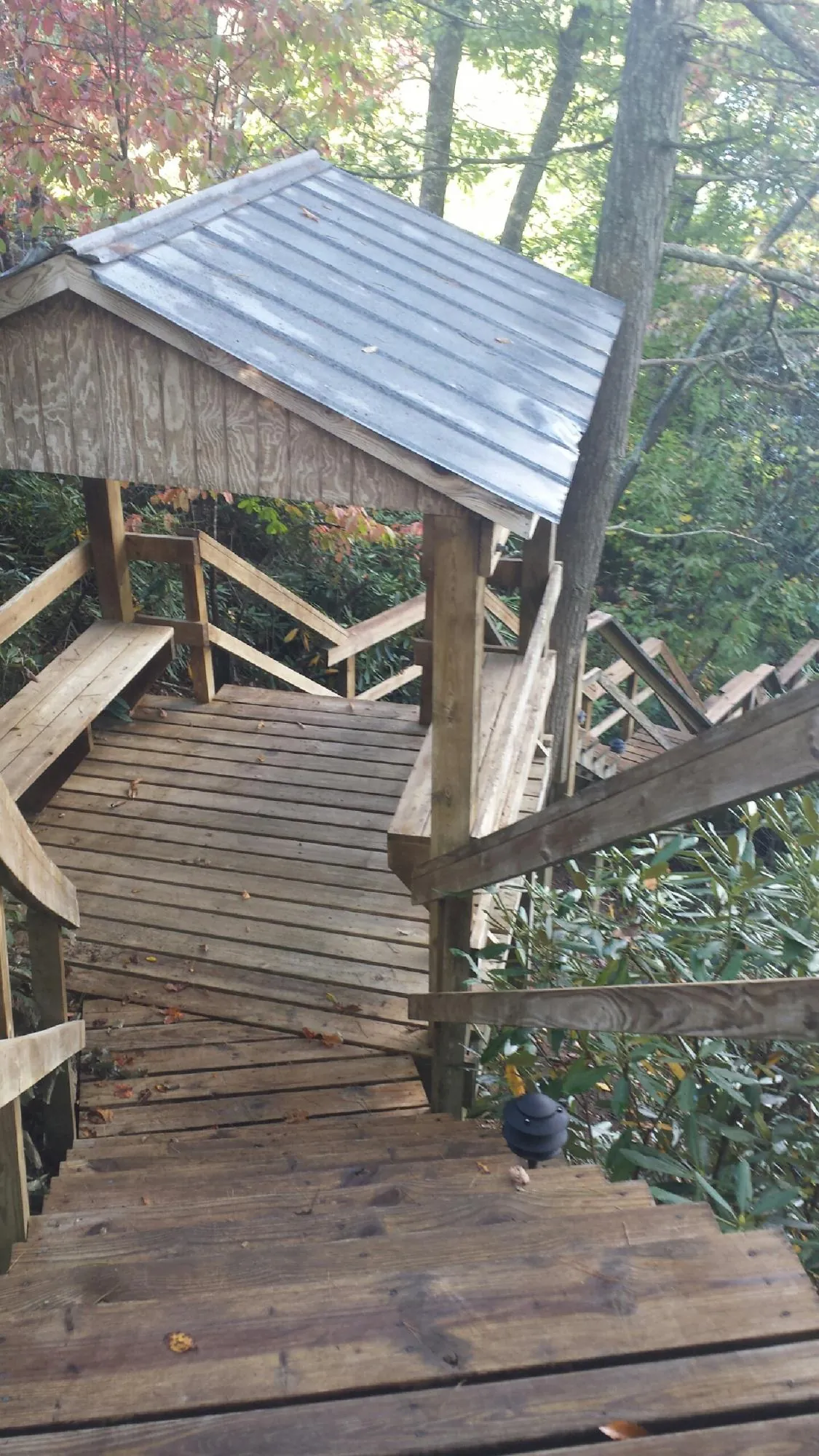 Metal roofed shelter over wooden steps on a wooded walkway — Skylight Repair & Installation work by our crew in Livermore Falls