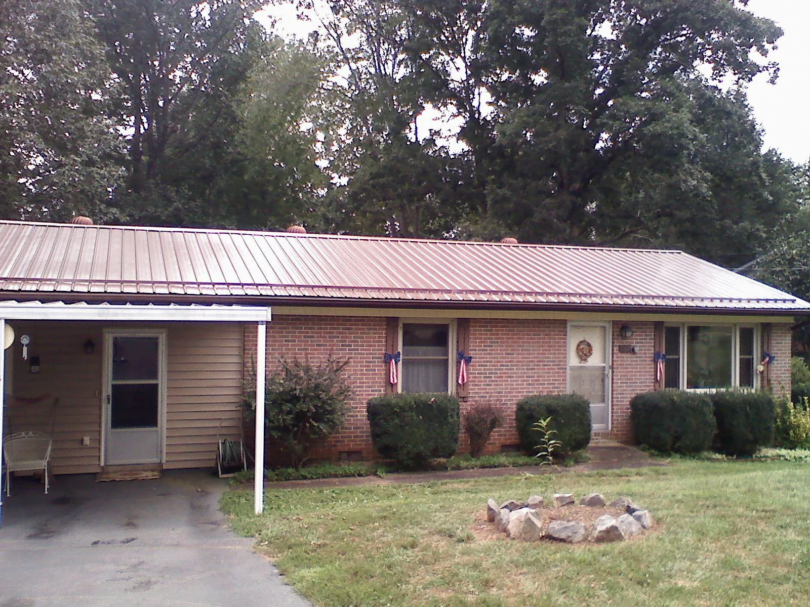 Bronze metal roof and carport on a brick ranch home — Roof Repair work by our crew in Livermore Falls